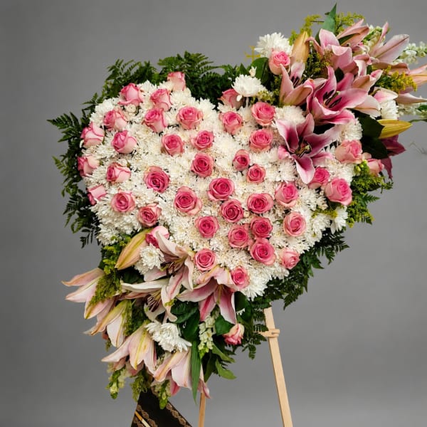 Heart-shaped floral spray with pink roses and lilies on an easel