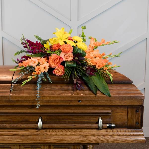 Colorful floral spray arranged on a wooden casket