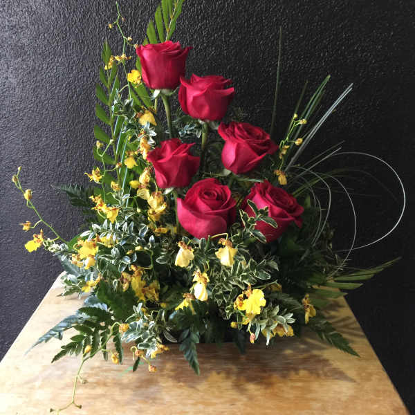 Red roses with yellow accent flowers in a low arrangement