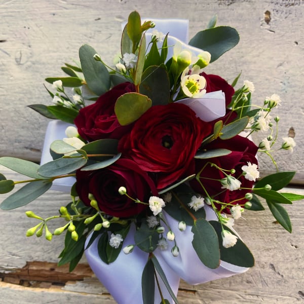 Bouquet of deep red roses with white filler flowers and eucalyptus wrapped in white paper