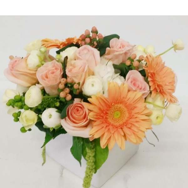 Peach and white bouquet with gerbera daisies and roses in a white container