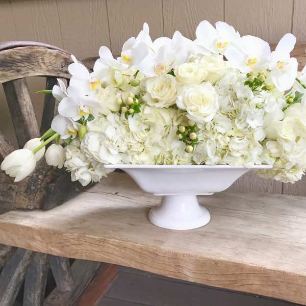 White floral arrangement in a white pedestal bowl