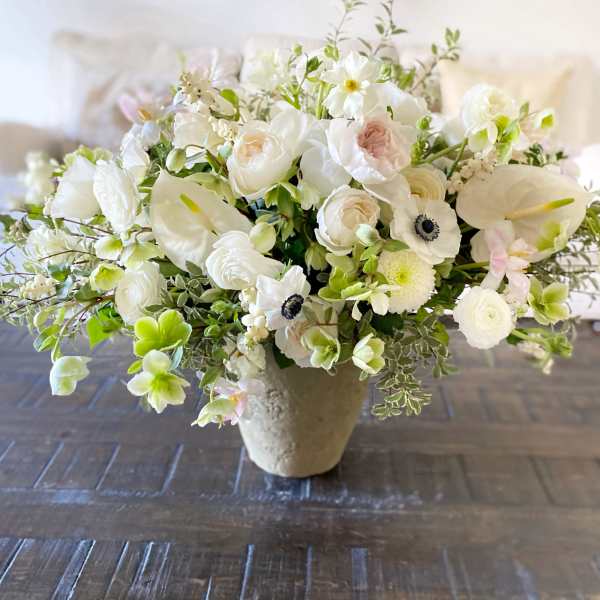 White floral arrangement in a beige vase with anemones and roses