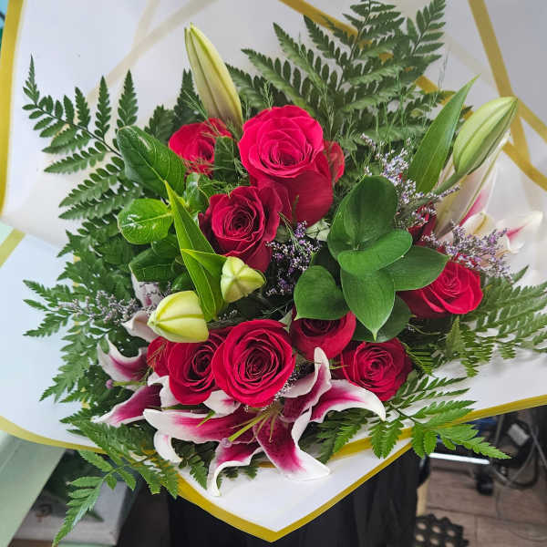 Bouquet of red roses and pink lilies with fern foliage