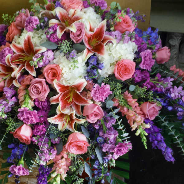 Large floral spray with pink roses, lilies, and purple flowers