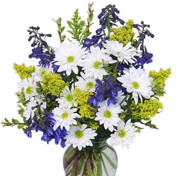 White daisies and blue flowers arranged in a clear glass vase