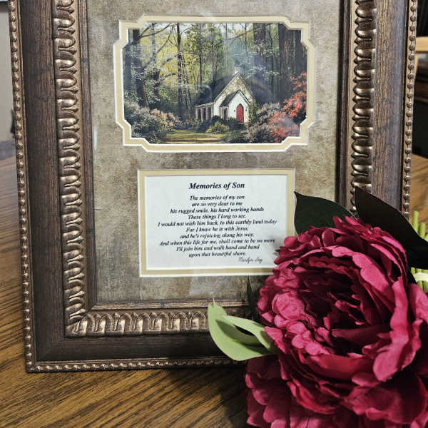 Framed memorial plaque with a pink flower accent
