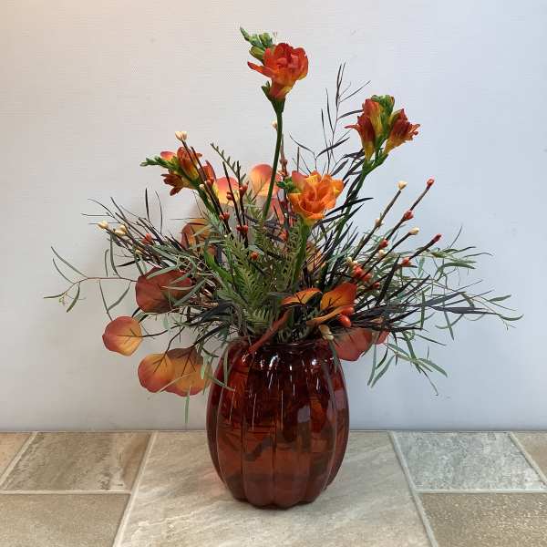 Orange floral arrangement in a brown glass vase