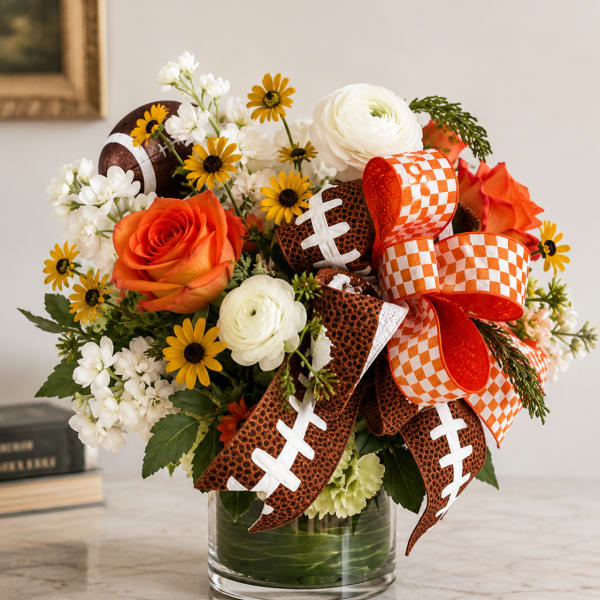 Bouquet of orange and white flowers in a glass vase with football ribbons