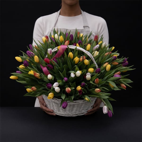 Basket of multicolored tulips held by a person