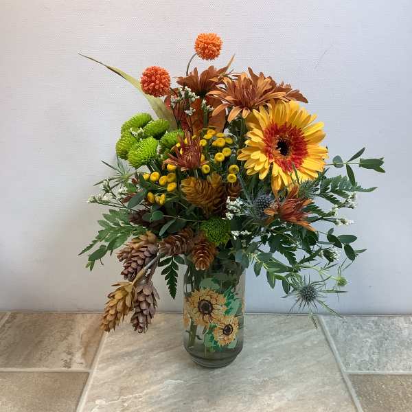 Mixed autumn bouquet in a glass vase with yellow and orange blooms