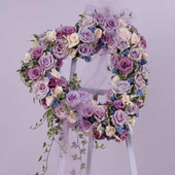 Lavender and pink rose wreath on a white stand with trailing greenery