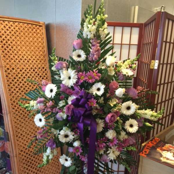 Tall standing floral spray with white and pink flowers and a purple ribbon