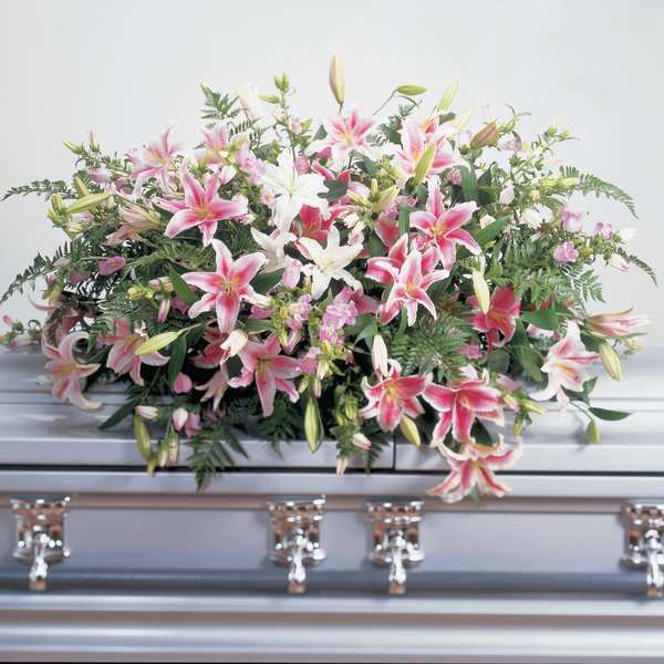 Pink and white lilies arranged on a casket