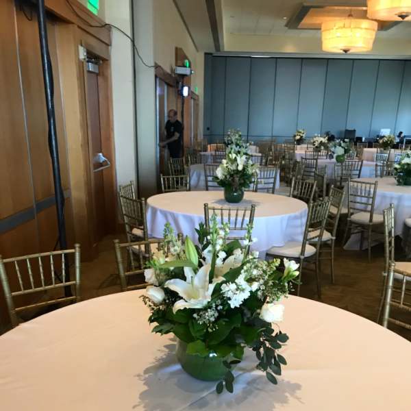 White floral centerpiece in a green vase on a round table
