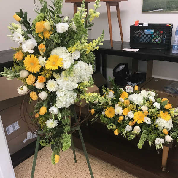 Large yellow and white floral standing spray with a matching low arrangement