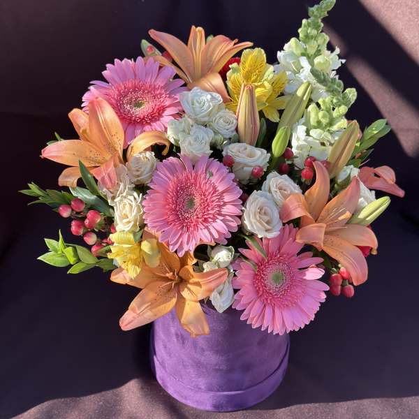 Pink gerberas, peach lilies, and white roses in a purple hat box