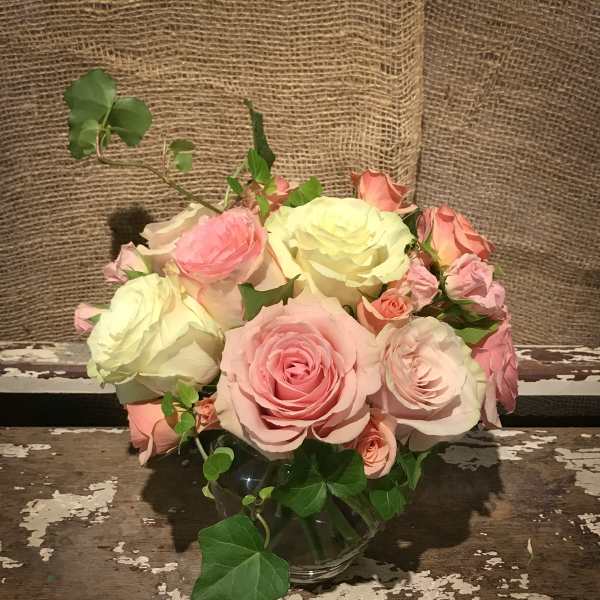 Pink and cream roses arranged in a clear glass vase