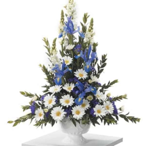 Tall blue and white floral arrangement in a white urn on a pedestal
