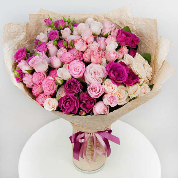 Bouquet of pink and white roses wrapped in beige paper with a ribbon