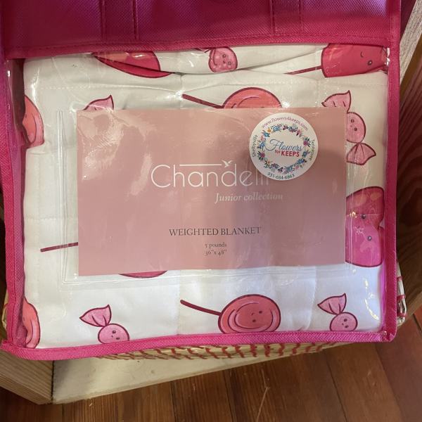 Pink tote bag holding a packaged weighted blanket with cherry print