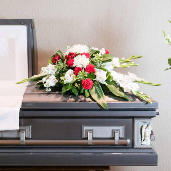 White and red floral spray arranged on top of a casket