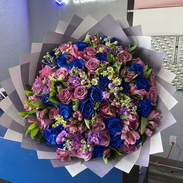 Large bouquet of pink and blue roses with small white filler flowers