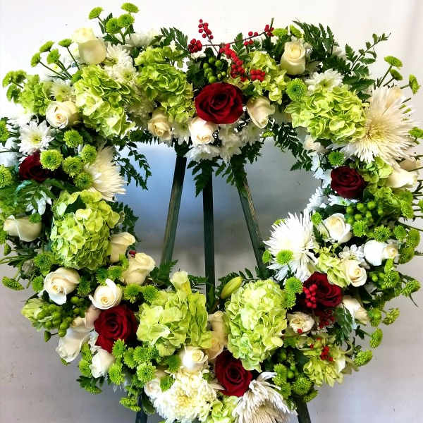 Heart-shaped floral wreath with red and white roses and green hydrangeas