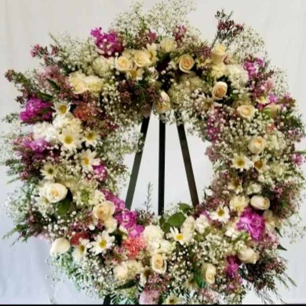 Large floral wreath with cream and pink flowers on a stand