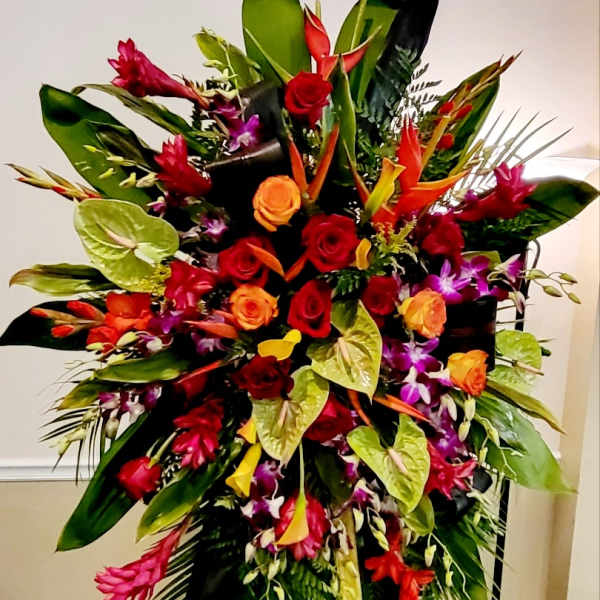 Large tropical floral arrangement with red and orange roses in a stand