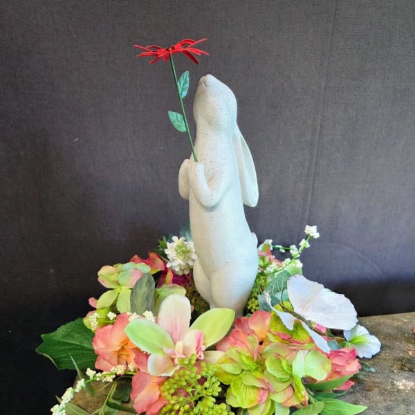 White rabbit figurine surrounded by pastel flowers and a red bloom on top
