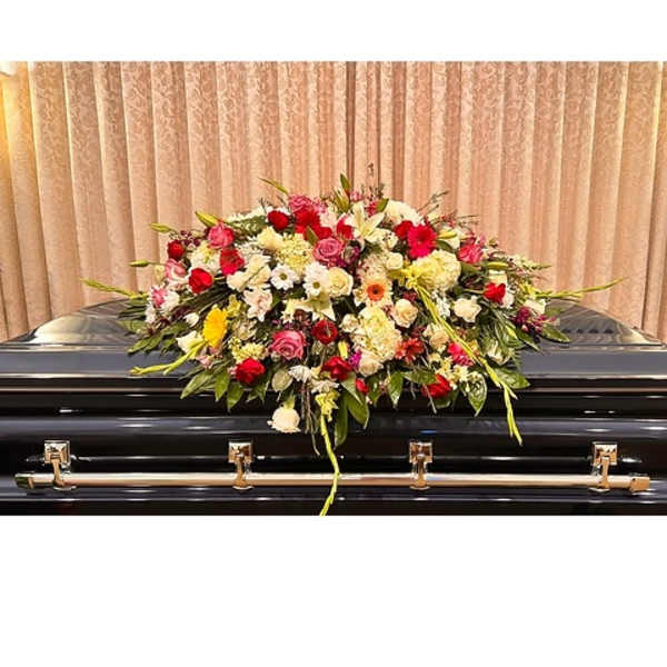Large floral spray on a black casket with red, pink, and white blooms