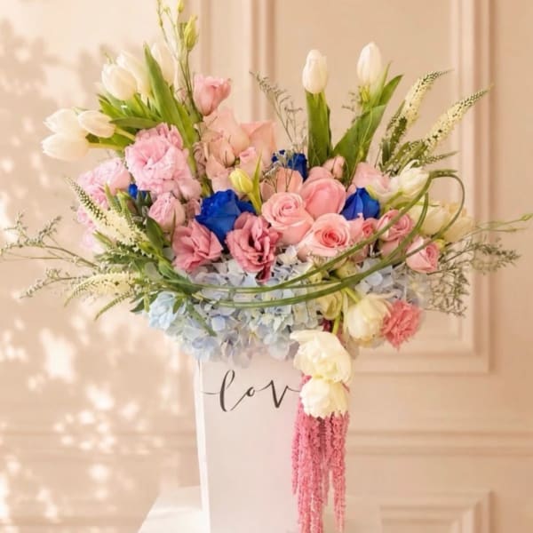 Pastel bouquet of roses, tulips, and hydrangeas in a white vase