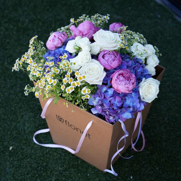 Mixed pink, white, and blue flowers in a cardboard gift box