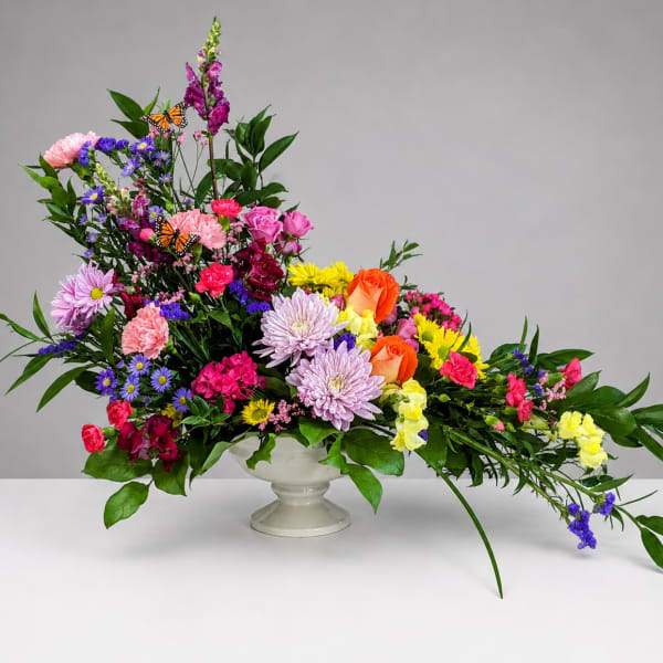 Colorful mixed flower arrangement in a white pedestal vase