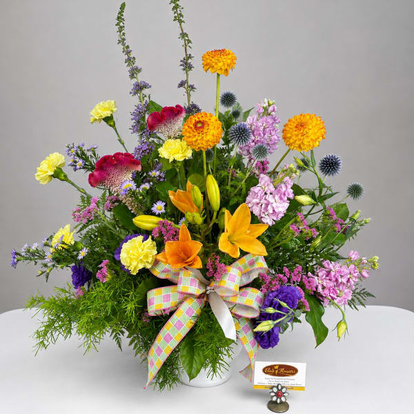 Colorful mixed bouquet in a white vase with a plaid ribbon