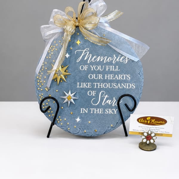 Blue memorial plaque with gold ribbon and star accents on a stand