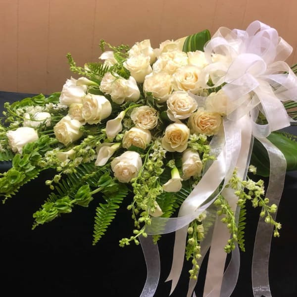 Cream rose bouquet with white ribbon and trailing greenery