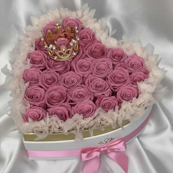Heart-shaped box of pink roses with a small crown topper