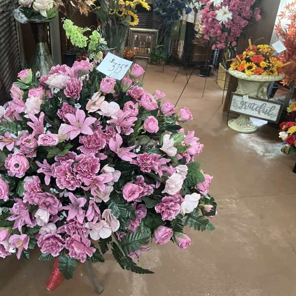 Large pink floral arrangement with roses and lilies in a shop display