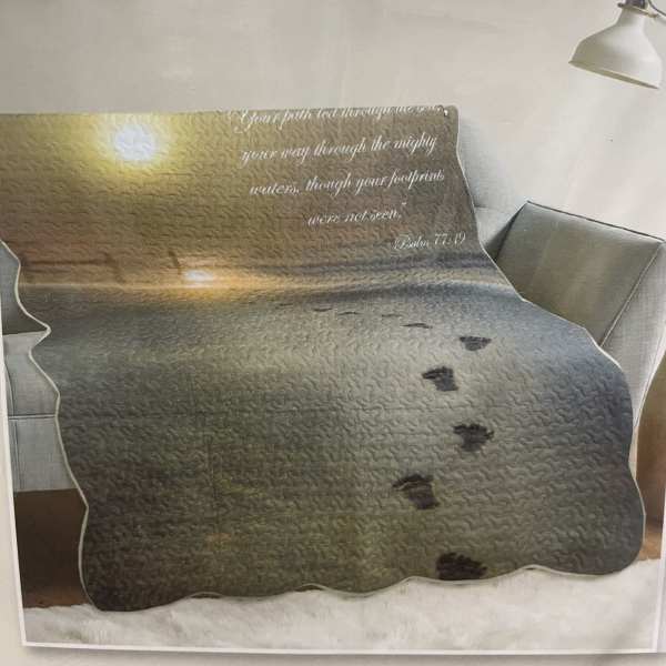 Printed blanket on a sofa with a sunset scene and Bible verse