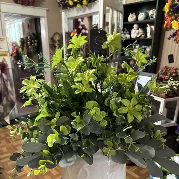 Green floral arrangement in a white ceramic pot
