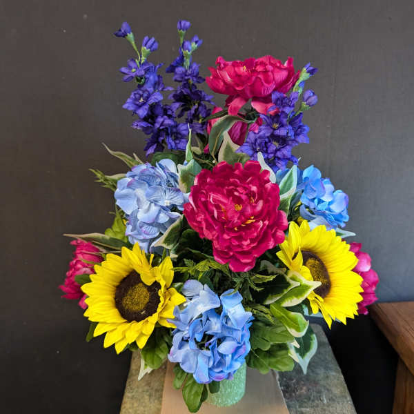 Colorful bouquet with sunflowers, blue hydrangeas, and pink peonies in a vase