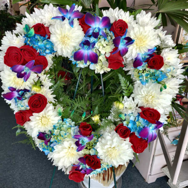 Heart-shaped floral wreath with red roses, white daisies, and blue orchids