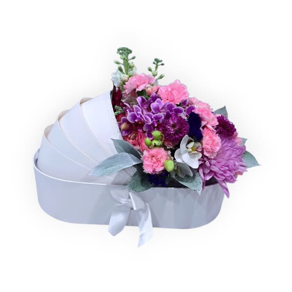 Mixed pink and purple bouquet in a white heart-shaped box with ribbon