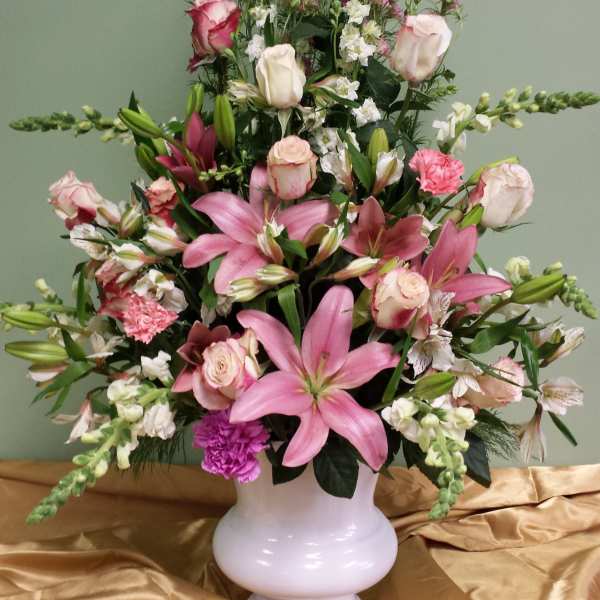Pink lilies and roses arranged in a white vase