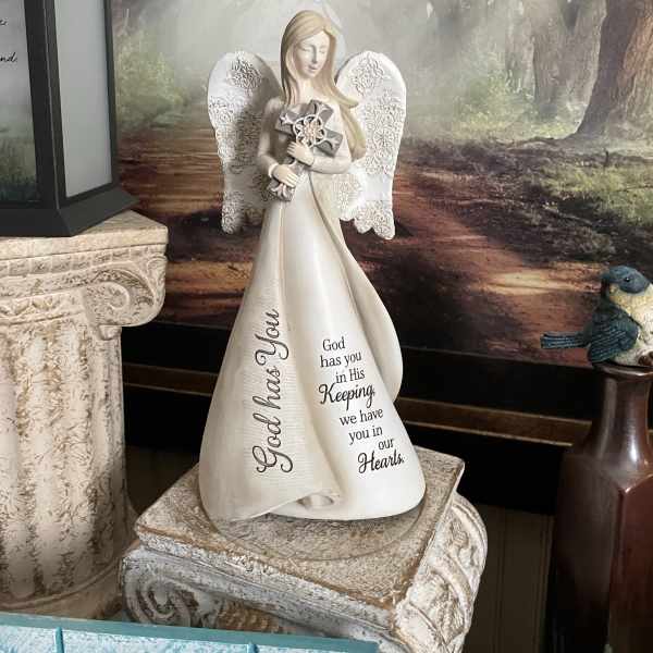 Angel figurine holding a cross with memorial text on the robe