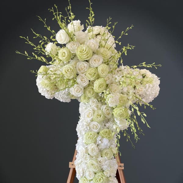 White and pale green floral cross on a wooden stand
