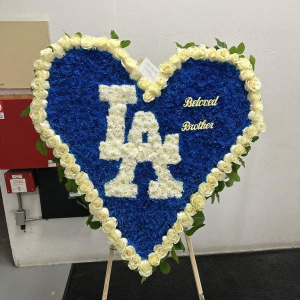 Heart-shaped blue floral tribute with white roses and "LA" lettering