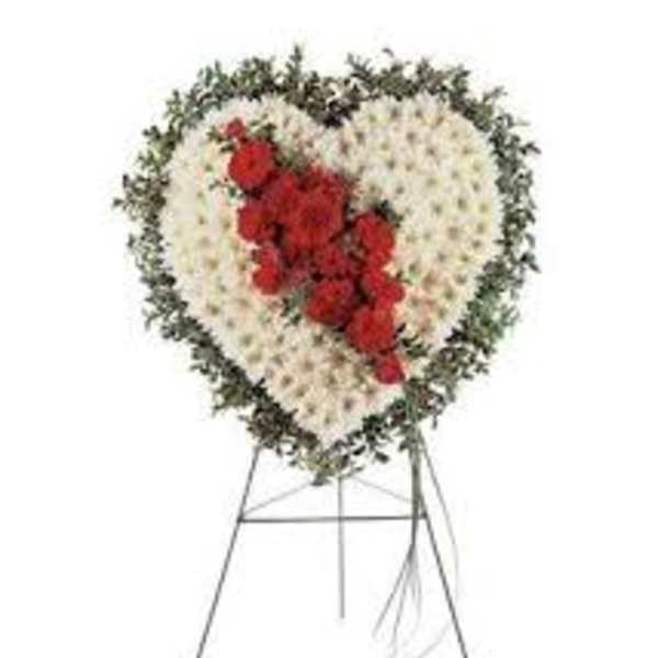 Heart-shaped funeral wreath with white flowers and red roses on a stand